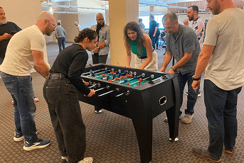 A group of people playing foosball together in a large, open indoor space.