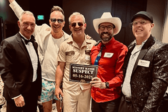Five men in costumes pose with a 'Mystery Manor Suspect' sign dated 05-16-2025 at a themed event.